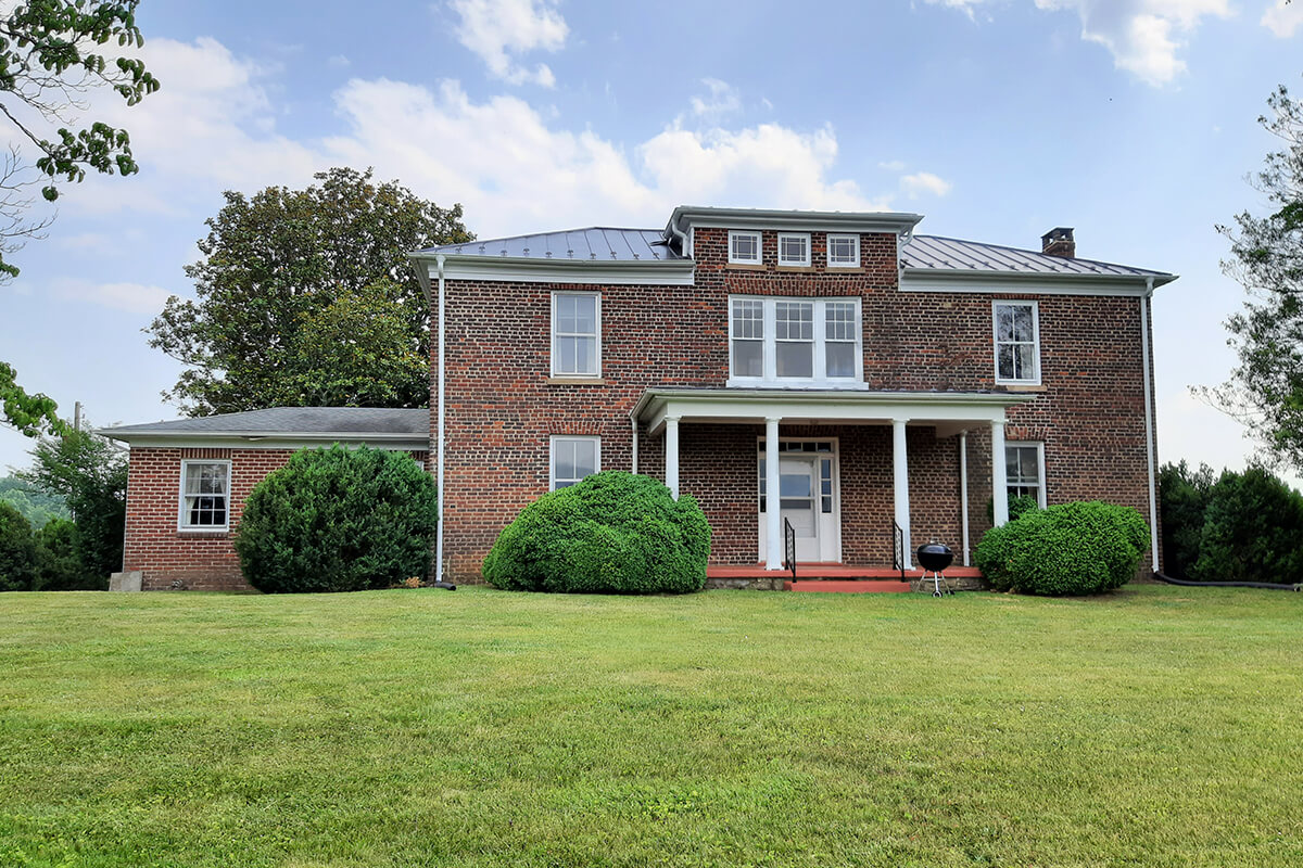 Brick house with white trim, front porch, and manicured lawn