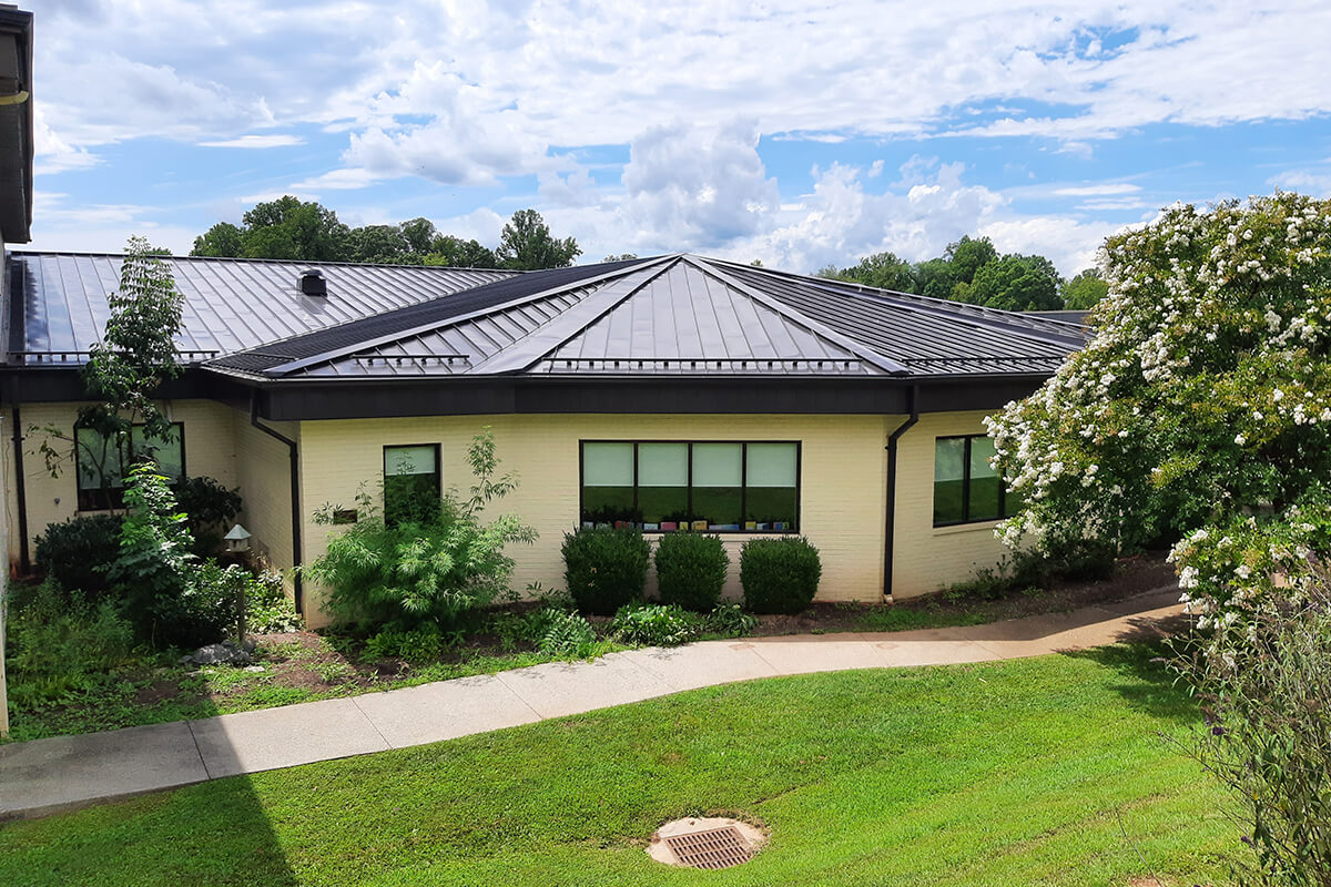 Single-story building with metal roof and surrounding greenery