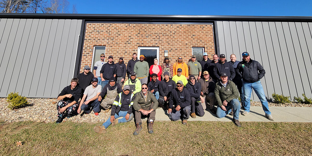 The Traditional Roofing team posing in front of a brick and metal building