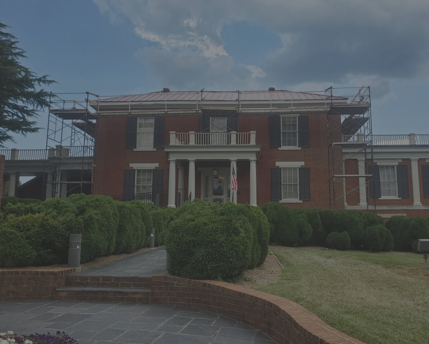 Large brick house with scaffolding and trimmed bushes