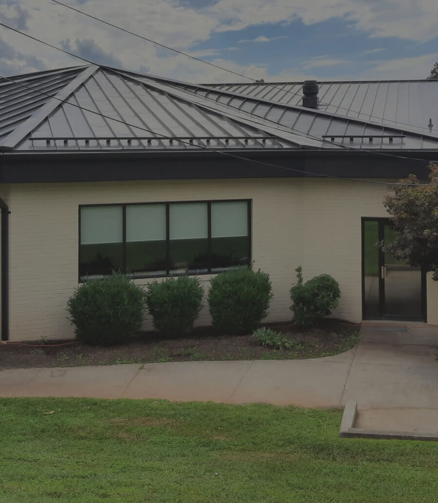 Single-story building with metal roof and trimmed bushes