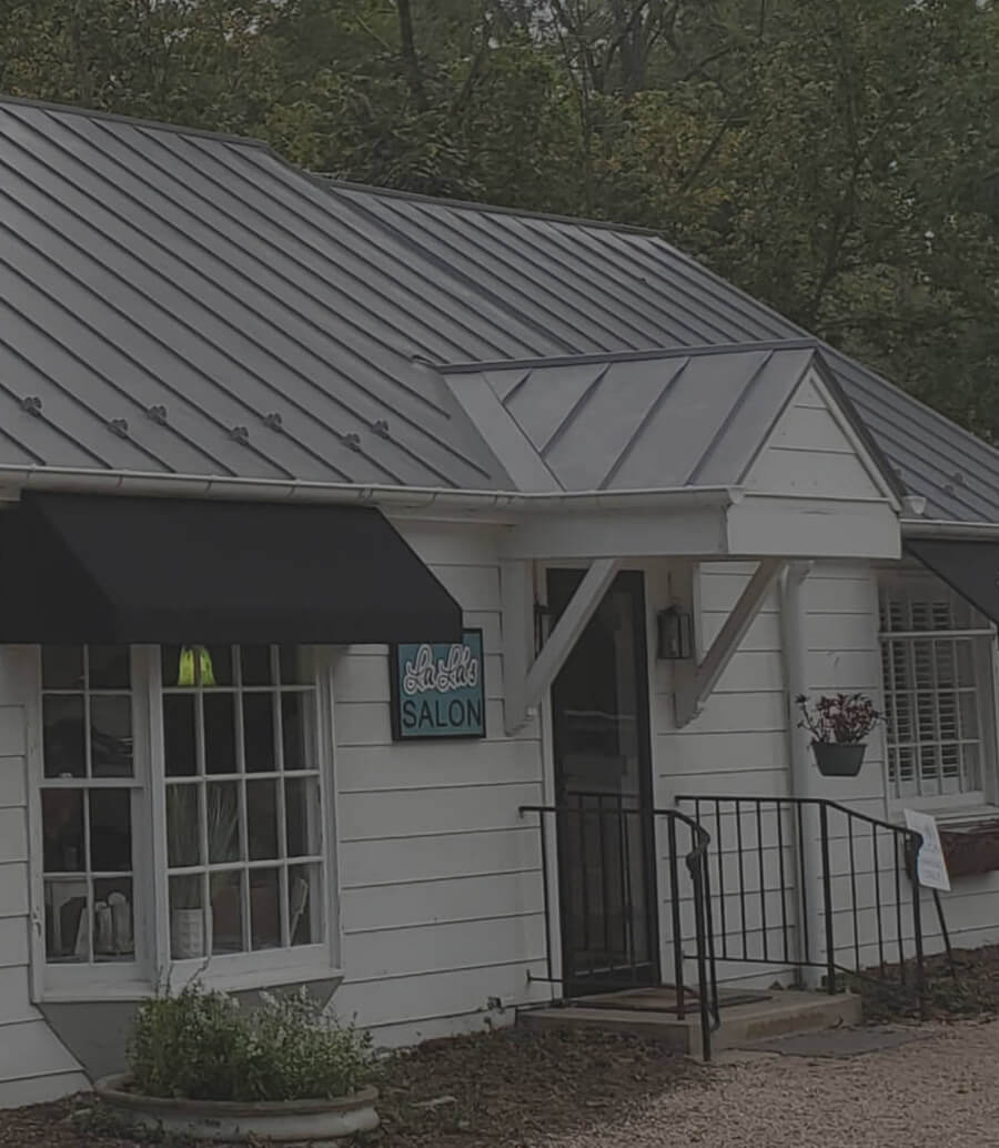 Small white salon with metal roof and black awning